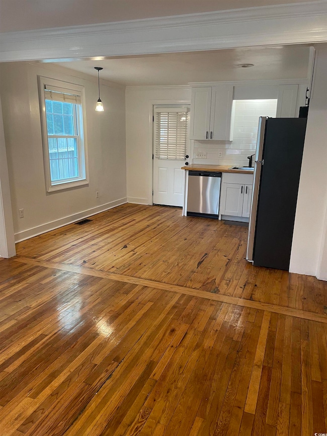Kitchen with light wood-style flooring, backsplash, white cabinets, appliances with stainless steel finishes, and crown molding
