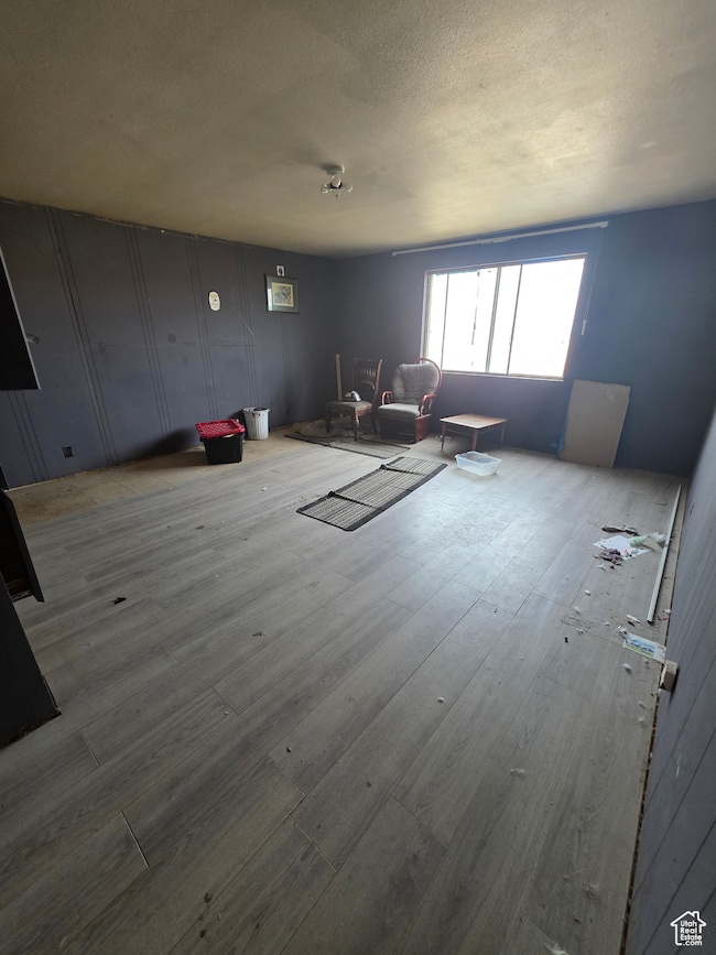 Living room featuring wood finished floors, a textured ceiling, and a decorative wall