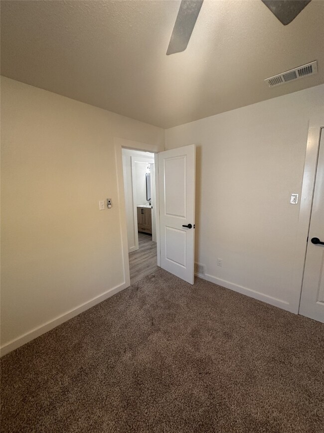 Spare room featuring dark colored carpet, a textured ceiling, and a ceiling fan