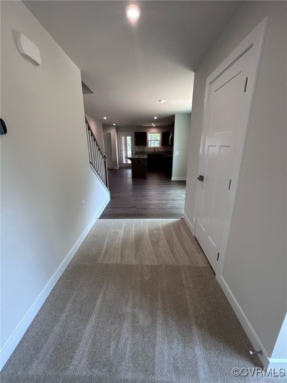 Hallway featuring dark colored carpet, stairs, bas