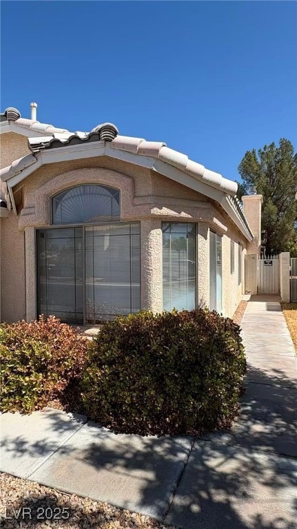View of home's exterior with stucco siding and a gate