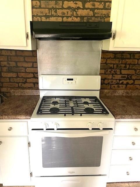 Kitchen with white cabinets and white range with g