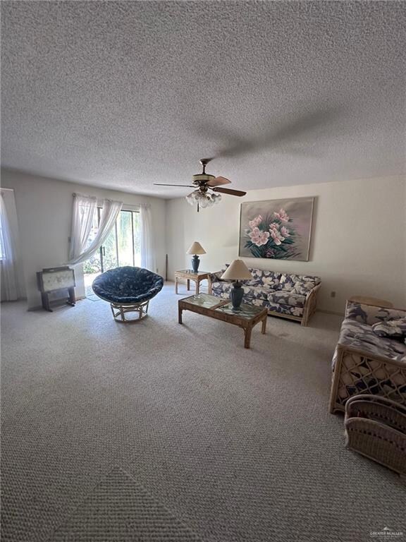 Living room with carpet, ceiling fan, and a textured ceiling