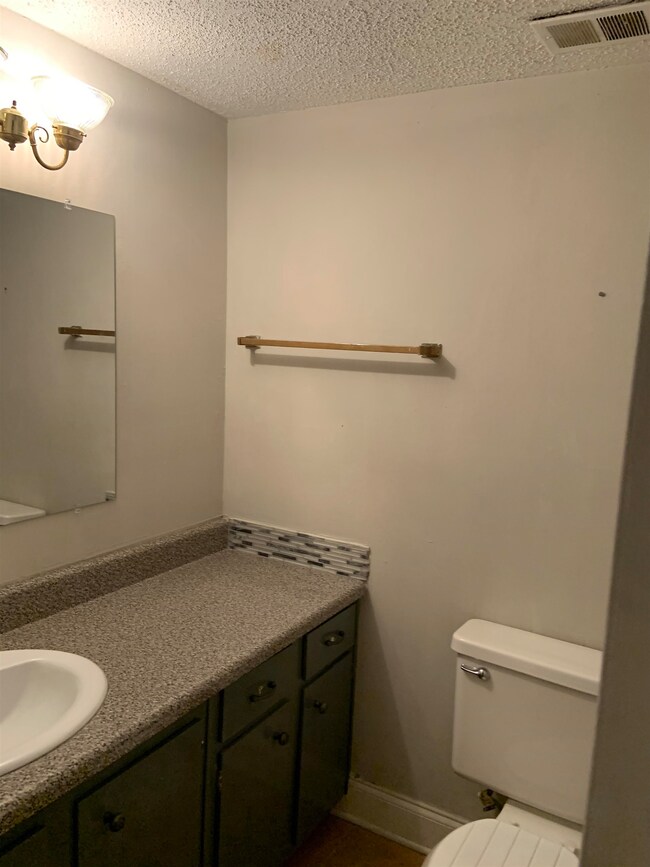 Bathroom featuring toilet, visible vents, a textur