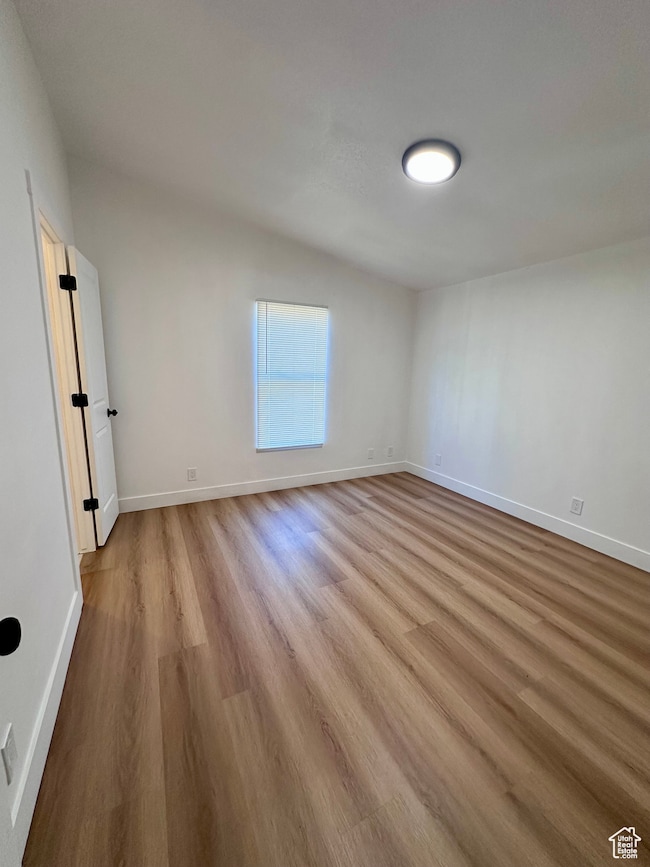 Spare room with light wood-style floors and lofted ceiling