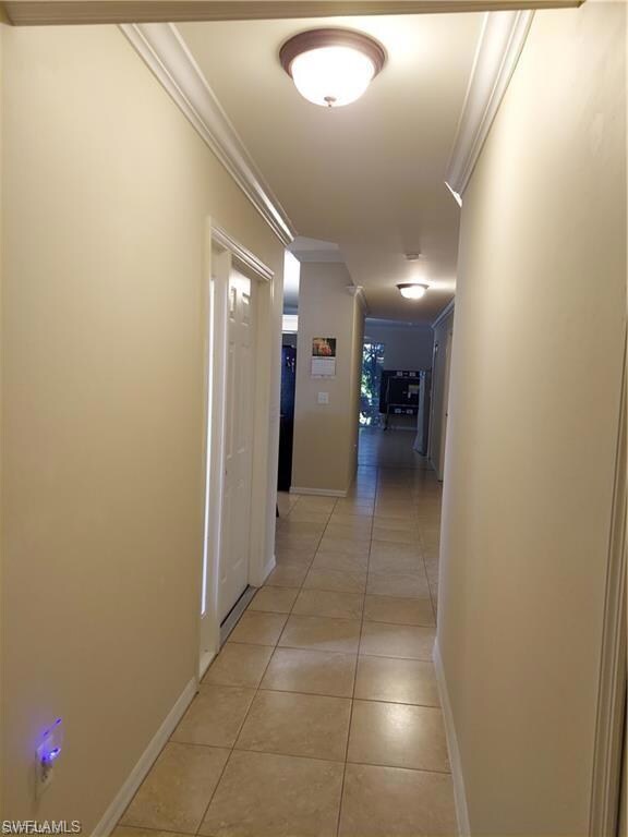 Hall with crown molding and light tile patterned floors