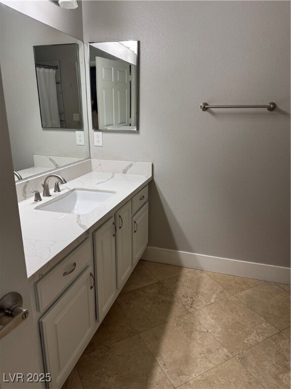 Full bath with vanity and baseboards