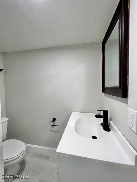 Bathroom featuring vanity, toilet, and baseboards