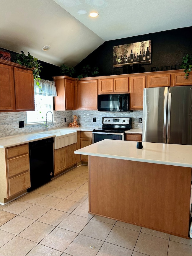 Kitchen with black appliances, vaulted ceiling, backsplash, brown cabinets, and light tile patterned flooring
