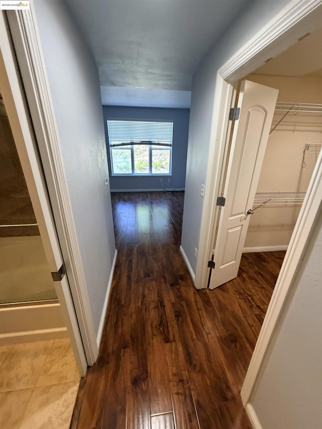 Hall with dark wood-style floors and baseboards
