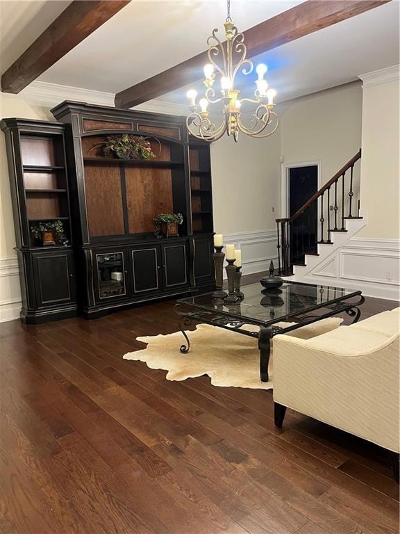 Dining space with beam ceiling, hardwood / wood-style flooring, a chandelier, a decorative wall, and ornamental molding