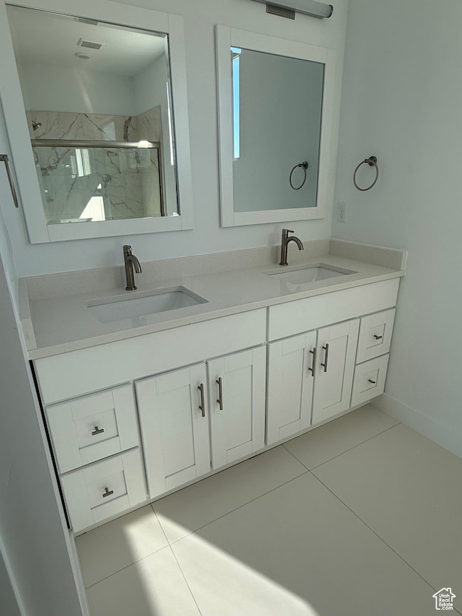 Full bath featuring light tile patterned floors, a marble finish shower, and double vanity
