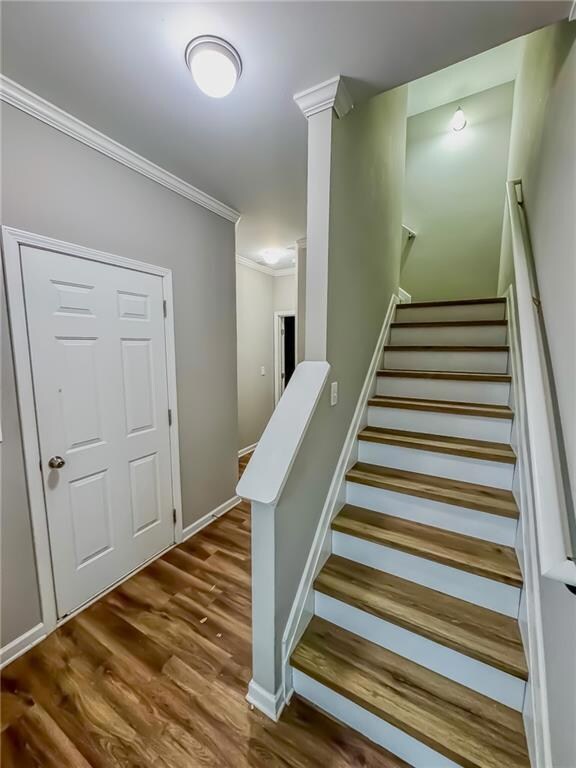 Staircase featuring crown molding and wood finished floors