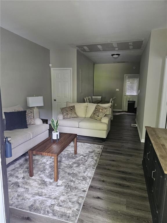 Living room featuring dark wood-style floors and baseboards