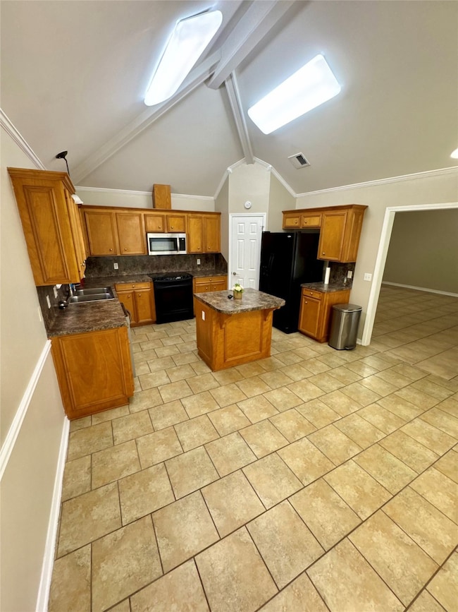 Kitchen featuring backsplash, brown cabinets, black appliances, crown molding, and a center island