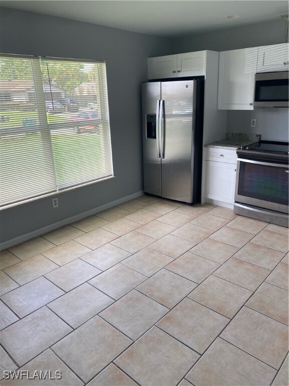 Kitchen featuring fridge, range, light tile patter