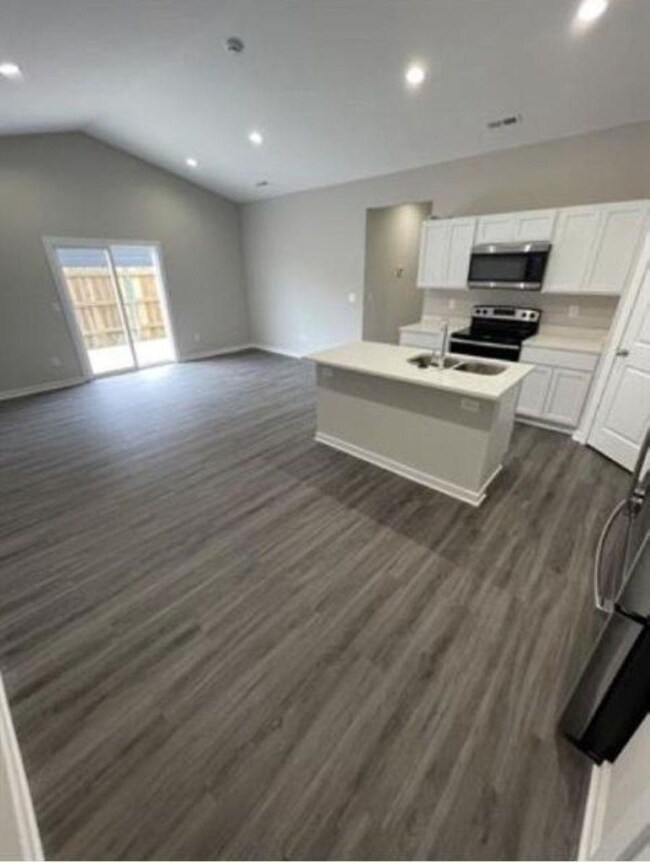 Kitchen featuring open floor plan, appliances with stainless steel finishes, dark wood-style flooring, and a sink