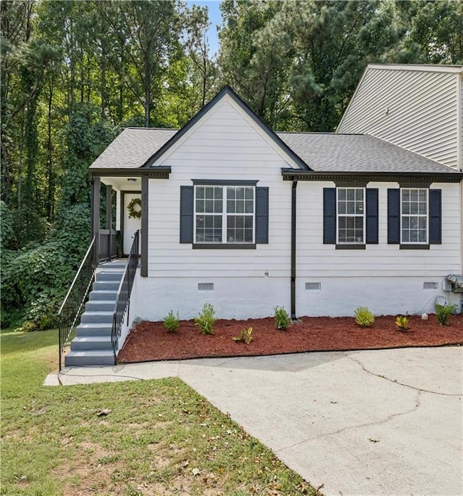 View of front of property with shingled roof, stairs, covered porch, and a front yard