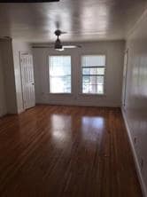 Unfurnished living room with healthy amount of natural light, dark wood-type flooring, and ceiling fan