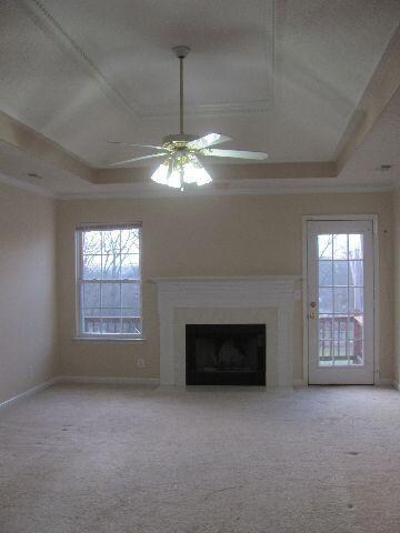 Living Room has tray ceiling and fireplace. Door leads to deck area