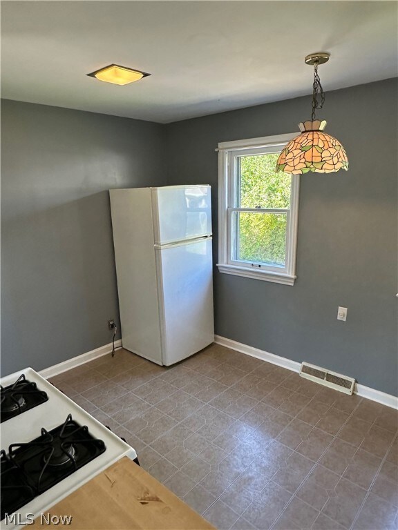 Kitchen featuring hanging light fixtures, a wealth of natural light, dark tile flooring, and backsplash