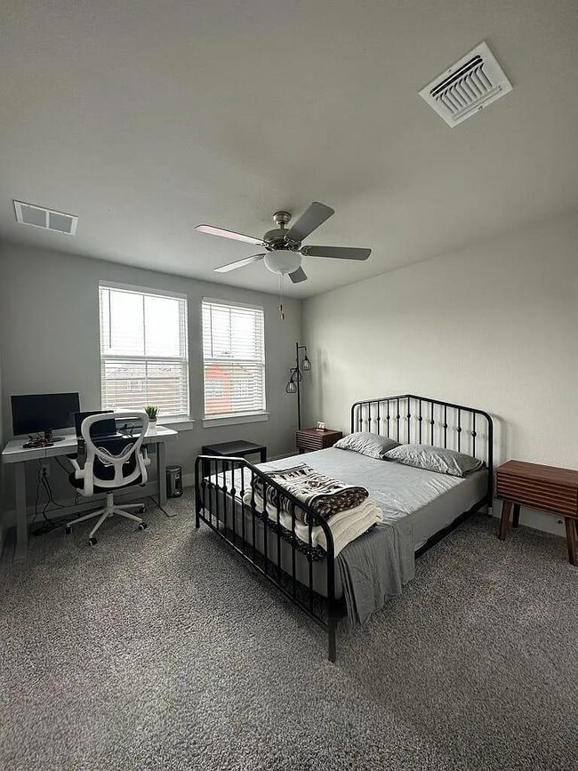 Carpeted bedroom featuring a desk, a ceiling fan,