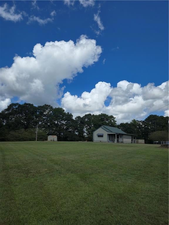 View of green lawn with a shed and view of scattered trees