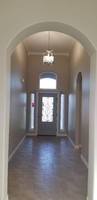 The inviting extra long and spacious entry foyer with a beautiful front door and light fixture; left side archway is to the 3 bedrooms and hallway bathroom.