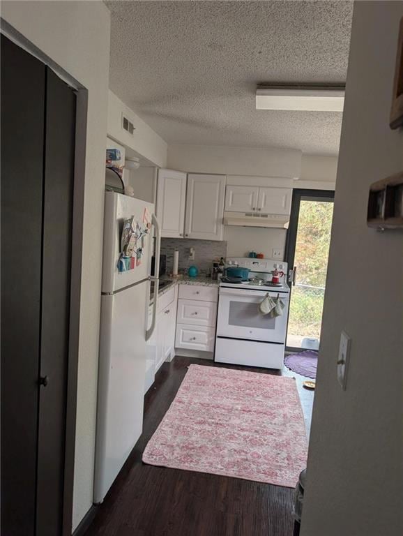 Kitchen featuring a textured ceiling, white appliances, white cabinets, dark wood finished floors, and backsplash
