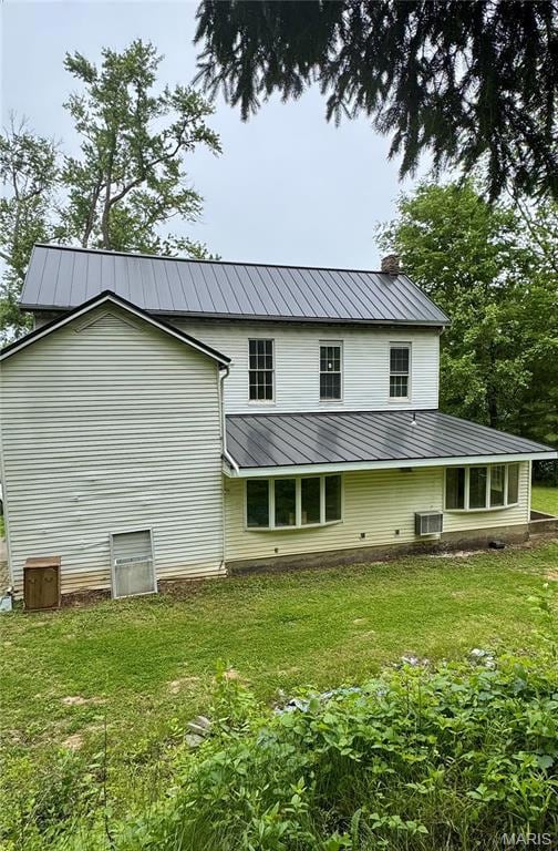 Rear view of house with a chimney, metal roof, a yard, and central AC unit