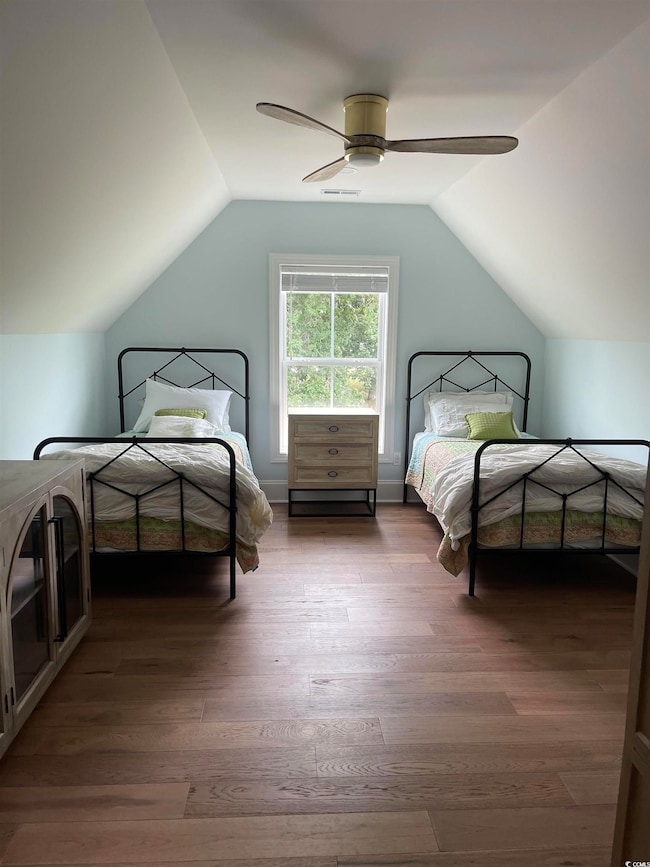 Bedroom with vaulted ceiling, wood finished floors, and ceiling fan
