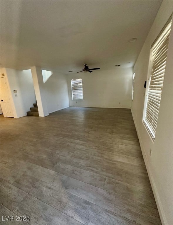Spare room featuring ceiling fan, stairs, and base
