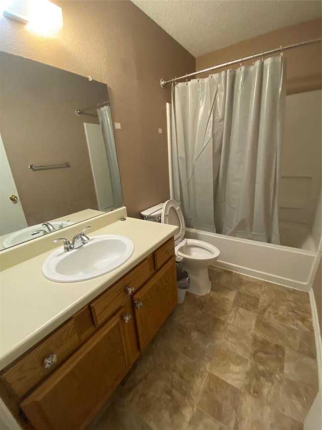 Bathroom featuring toilet, a textured ceiling, sho
