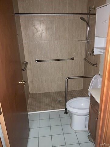 Bathroom featuring tile floors, tiled shower, toilet, and vanity