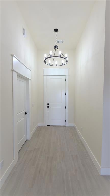 Doorway to outside featuring light wood-type flooring and a chandelier