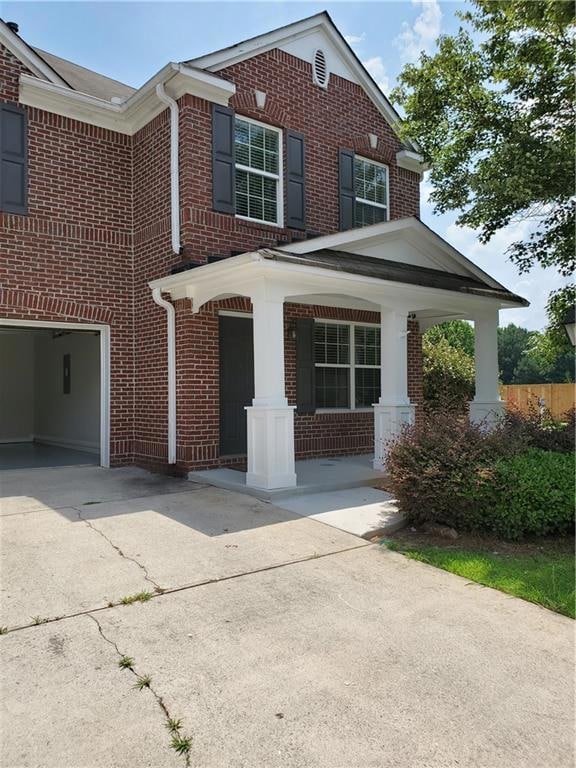View of front facade featuring brick siding, a porch, and concrete driveway
