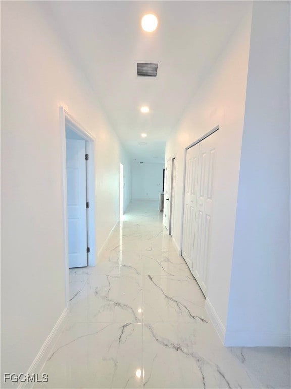 Hallway featuring recessed lighting and light marble finish floors