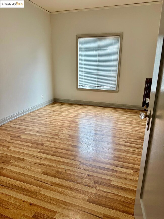 Spare room with wood finished floors and crown molding