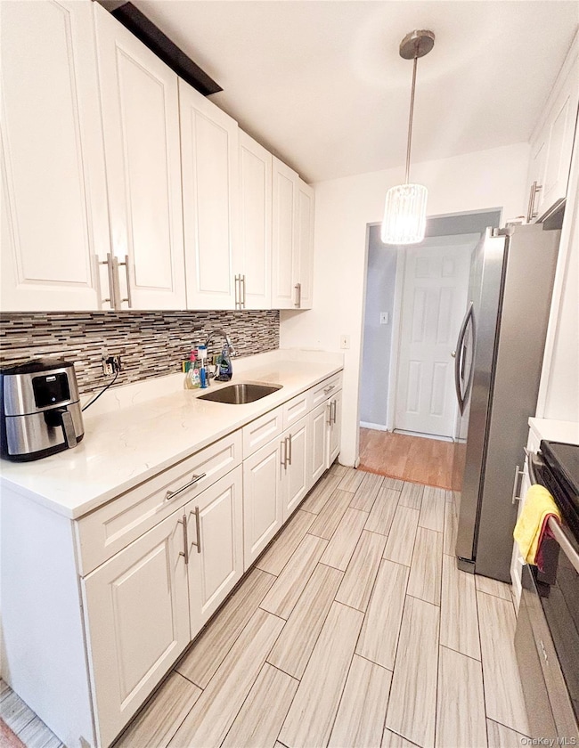 Kitchen featuring range, decorative backsplash, white cabinetry, wood finish floors, and light countertops