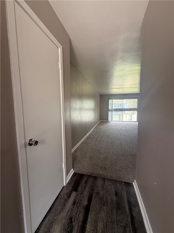 Hallway featuring dark wood-style floors and baseb