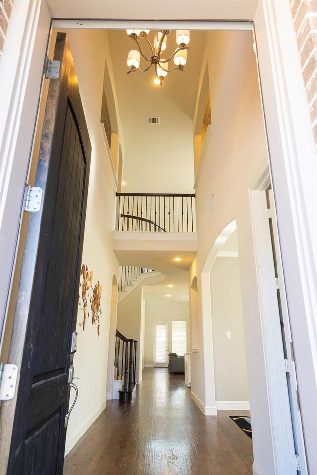 Entrance foyer featuring dark hardwood / wood-style floors, a notable chandelier, and a towering ceiling