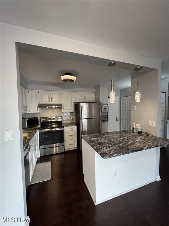 Kitchen featuring white cabinetry, appliances with stainless steel finishes, kitchen peninsula, and hanging light fixtures