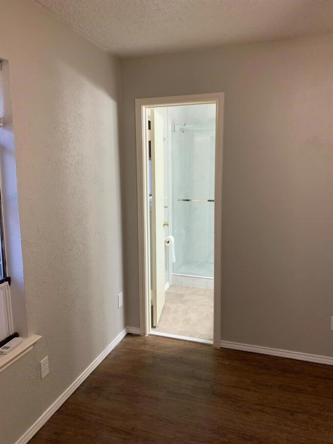 Corridor with a textured ceiling and dark hardwood / wood-style floors