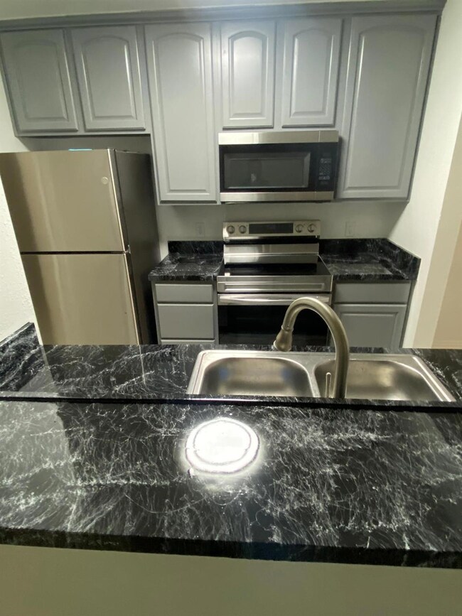Kitchen featuring dark stone counters, sink, and s