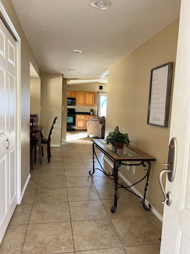 Hallway with light tile patterned floors and a textured ceiling