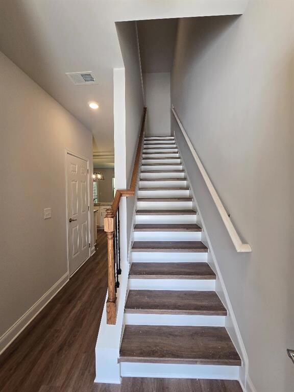 Staircase with wood finished floors and recessed lighting