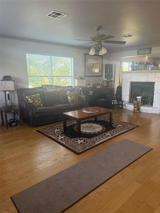 Living area featuring visible vents, ceiling fan,