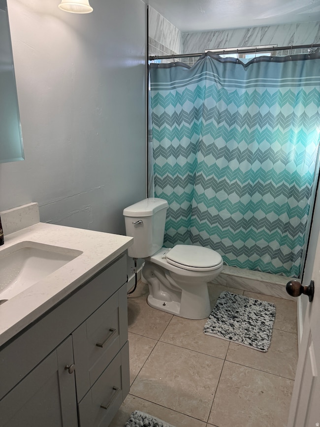 Bathroom with vanity, curtained shower, and light tile patterned floors
