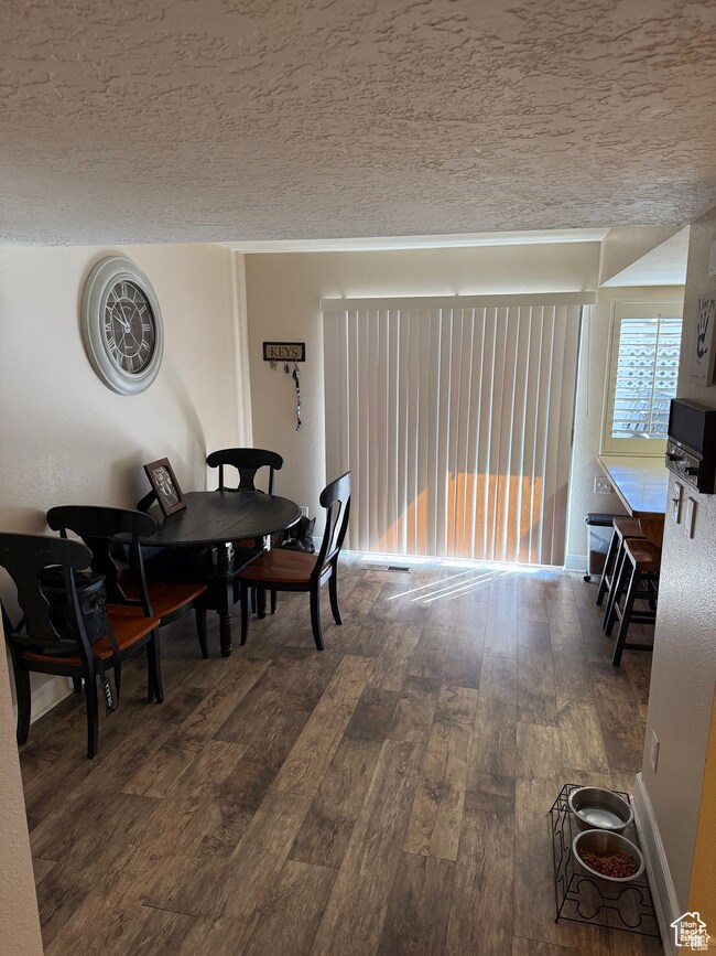 Dining space with a textured ceiling and dark wood-style floors