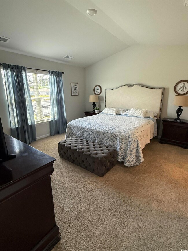 Carpeted bedroom featuring vaulted ceiling